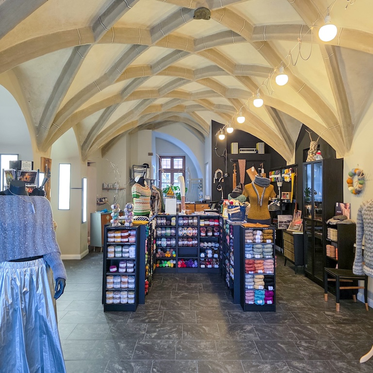 Ein Foto vom Innenraum der Wollkultur Wittenberg.
Ein Raum mit historischem Gewölbe und Regalen voller Wolle und Garnen.